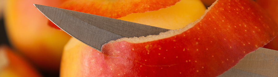 Close up of a knife peeling a peach