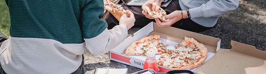 close up of people eating pizza