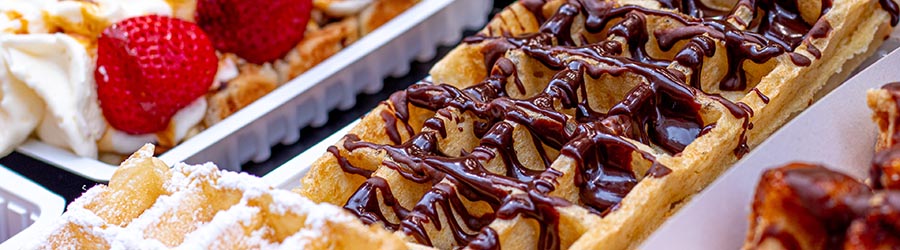 Close up of waffles with chocolate sauce, cream and strawberries